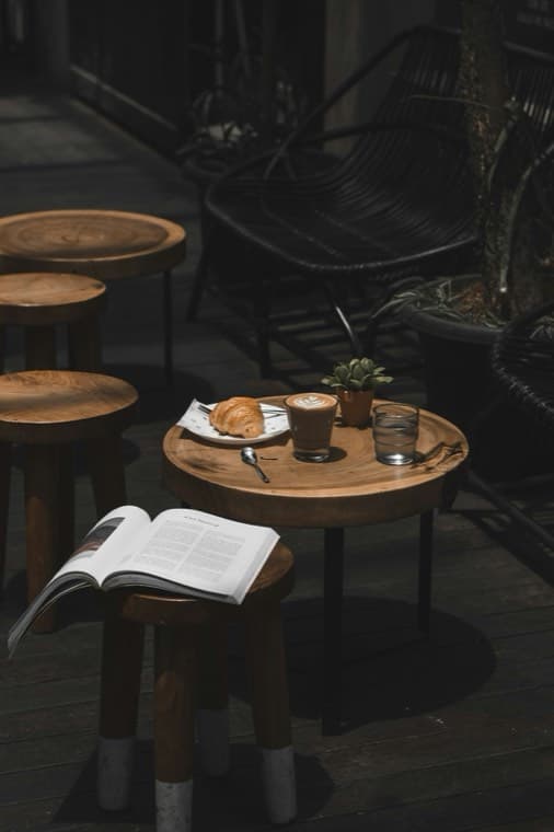 A coffee, a croissant and an open book on a small cafe table