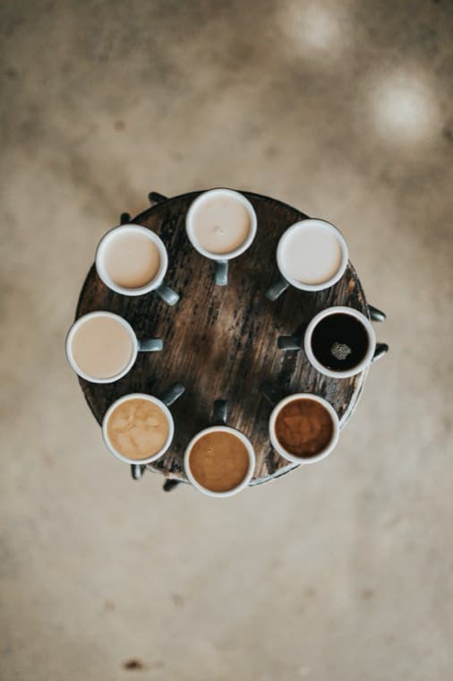 Flat whites arranged in a circle on a wooden table, shot from above