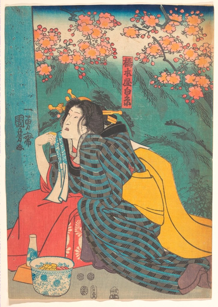 A Japanese woodblock print of a woman in a striped kimono seated beneath a branch of blossom.