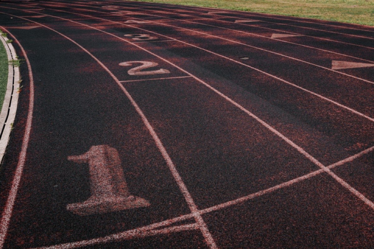 Lane numbers painted across a red synthetic track, shot low along the lane lines in flat light.